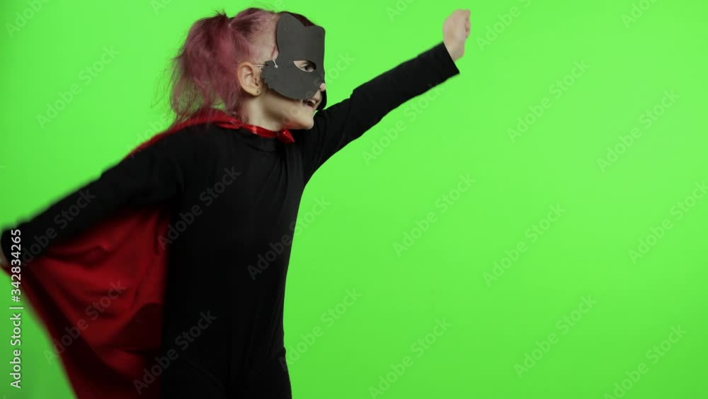Funny child girl in costume and mask plays super hero. National superhero day Funny child girl in costume and mask plays super hero. National superhero day