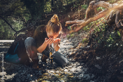 Young woman washes her face from mountain river. Tourism Adventure Bushcraft Survival Scout Concept