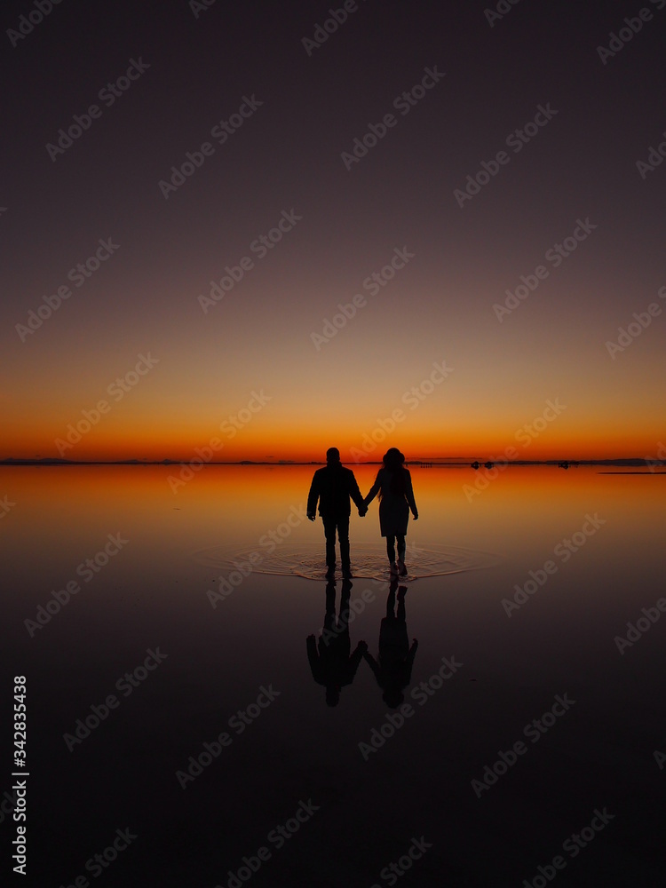 Couple hand by hand on the sunrise, Uyuni Salt Flat, Salar de Uyuni, Bolivia. Copy space for text Couple hand by hand on the sunrise, Uyuni Salt Flat, Salar de Uyuni, Bolivia. Copy space for text