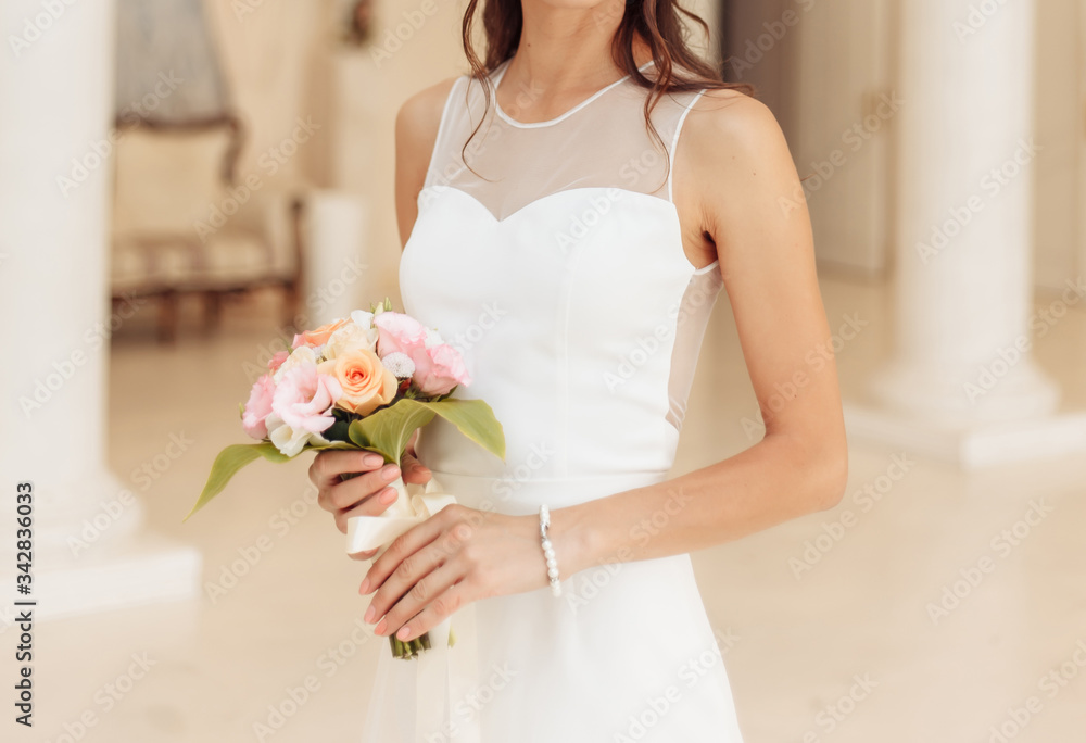 The bride holds a wedding bouquet of roses close-up.