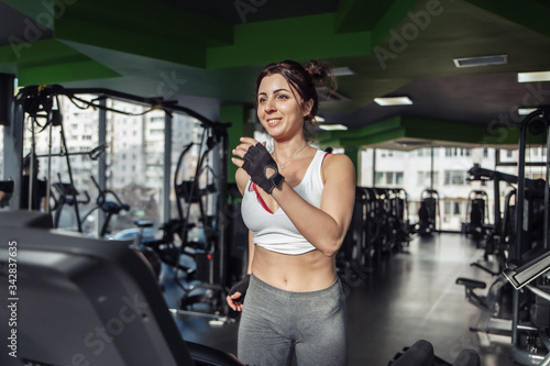 Cheerful slim fit woman in sportswear on a treadmill in the gym