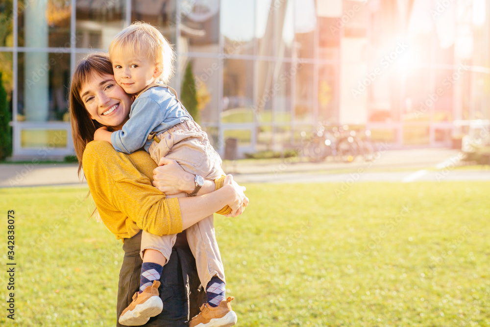 Fototapeta premium Happy young mother having fun with her kid - Son hugging his mum outdoor - Family connection, motherhood, love and tender moments concept - Focus on boy face