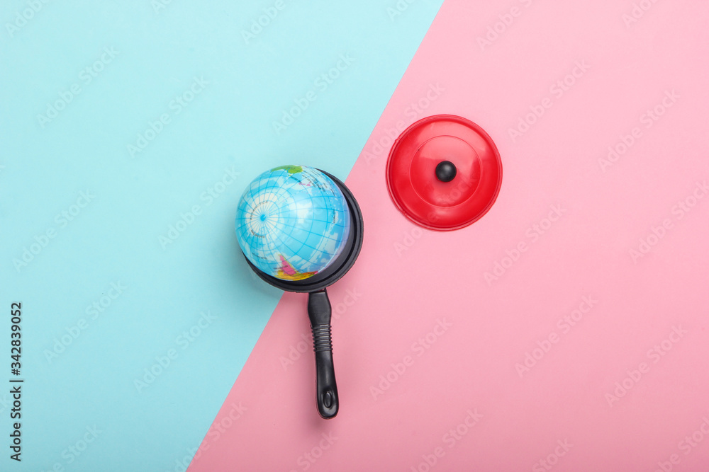 Global warming concept. Mini globe in a toy pan on a blue-pink pastel background. Top view. Minimalism. Climatic problems of our time. Top view Global warming concept. Mini globe in a toy pan on a blue-pink pastel background. Top view. Minimalism. Climatic problems of our time. Top view