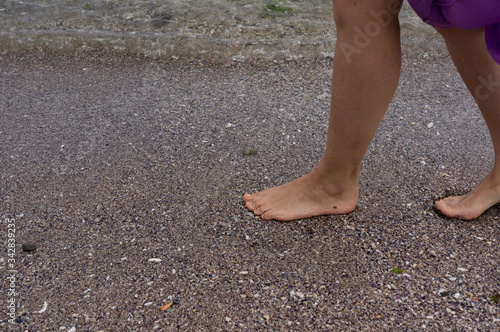Girls feet on the pebbles. Walking near the surf line.