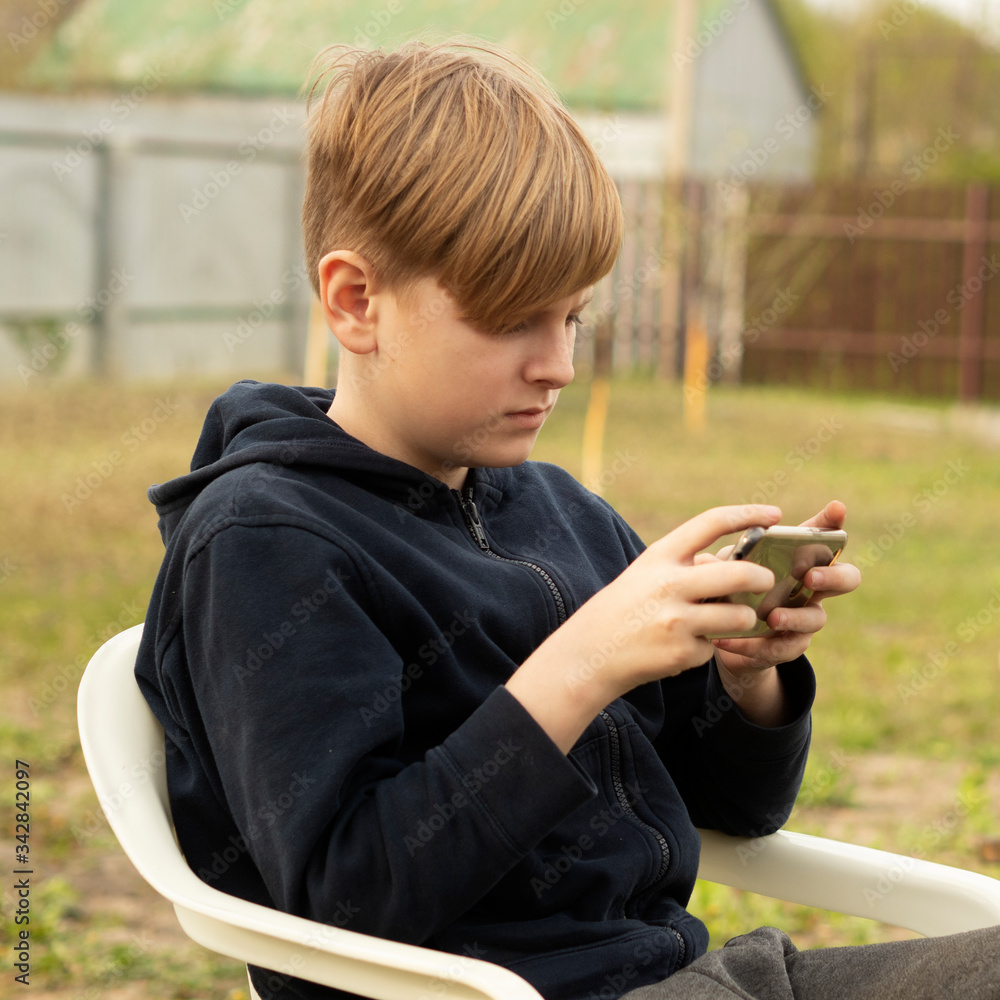 Caucasian blond boy plays on smartphone Caucasian blond boy plays on smartphone