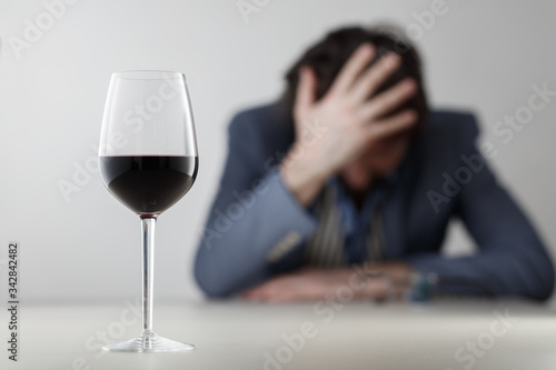 Glass with wine/ alcohol on blurred view of a lonely and desperate drunk man photo