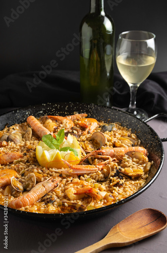 Seafood paella in rustic setting, cloudy wine
