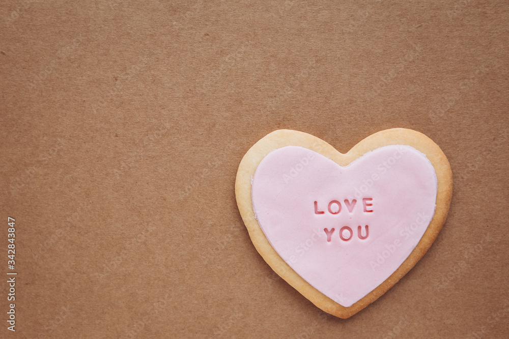Heart shaped cookies with pink glaze and the inscription: «love you» located on a craft paper background with space for your text..Valentine's Day gifts Heart shaped cookies with pink glaze and the inscription: «love you» located on a craft paper background with space for your text..Valentine's Day gifts