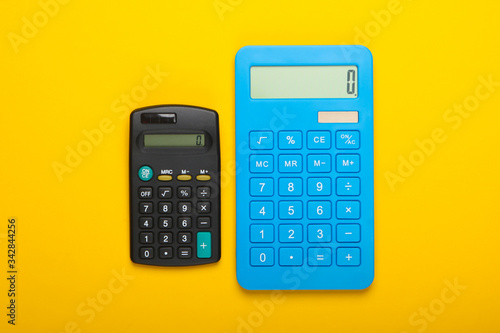 Two calculators on yellow background. Top view. © splitov27
