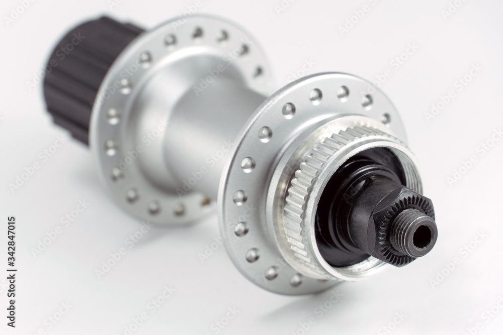 Bicycle repair. Mountain bike workshop. Rear hub under the disc brake on a white background. The body is silver. Spare parts for a bicycle of a famous manufacturer and brand. Bicycle repair. Mountain bike workshop. Rear hub under the disc brake on a white background. The body is silver. Spare parts for a bicycle of a famous manufacturer and brand.
