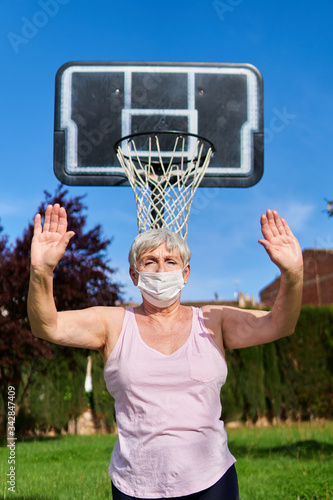 older woman with medical mask playing basketball