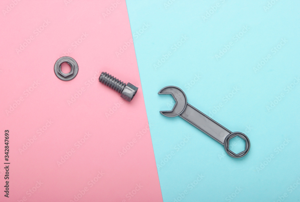 Toy wrench and nut with a bolt on a blue-pink pastel background. Top view Toy wrench and nut with a bolt on a blue-pink pastel background. Top view