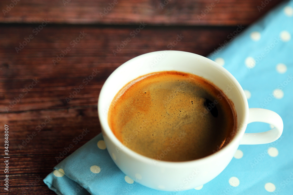 Fototapeta premium A cup of hot coffee on light blue fabric on wooden table, Hot espresso.