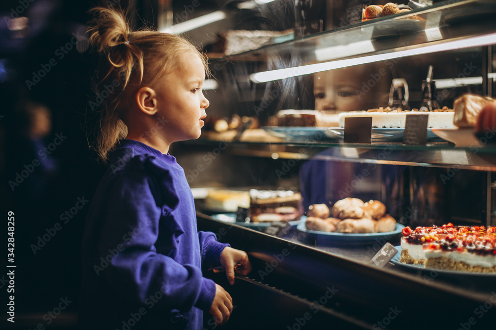 little pretty girl chooses pastries in a cafe. a child next to a showcase with goods