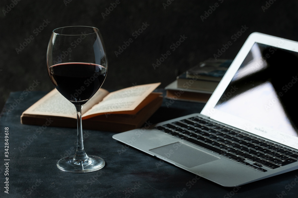 Copa de vino tinto, laptop y libro. Copa de vino tinto, laptop y libro.