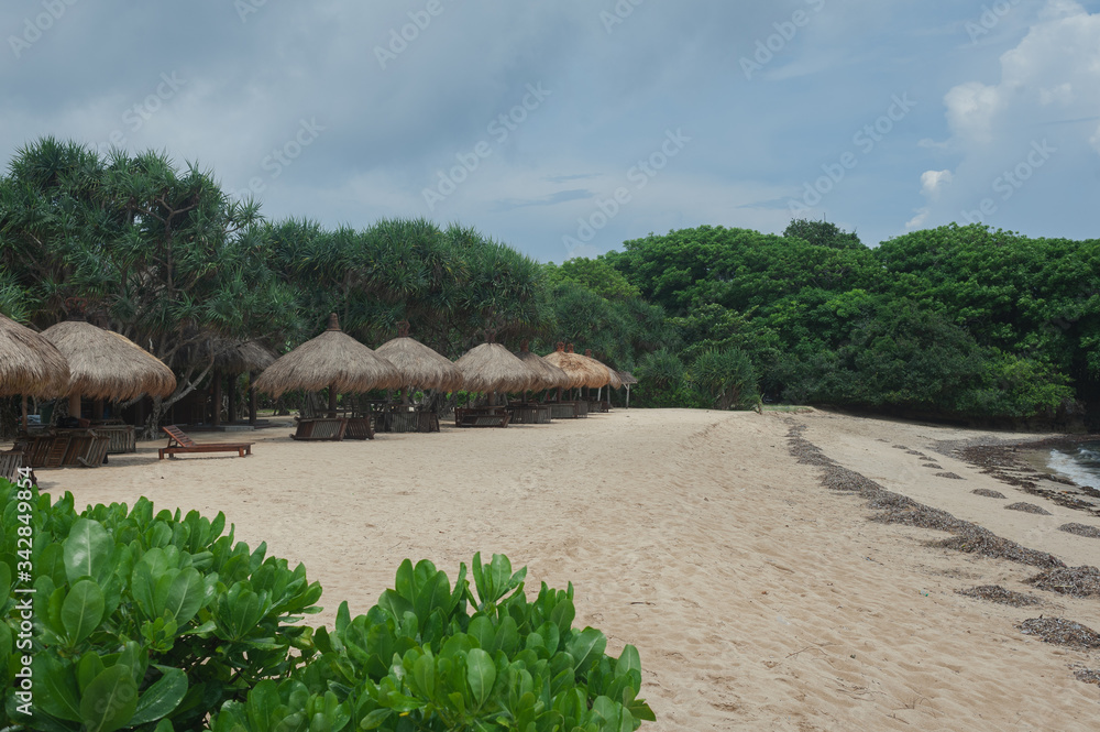 Fototapeta premium Beach umbrellas from straw on tropical sandy beach.
