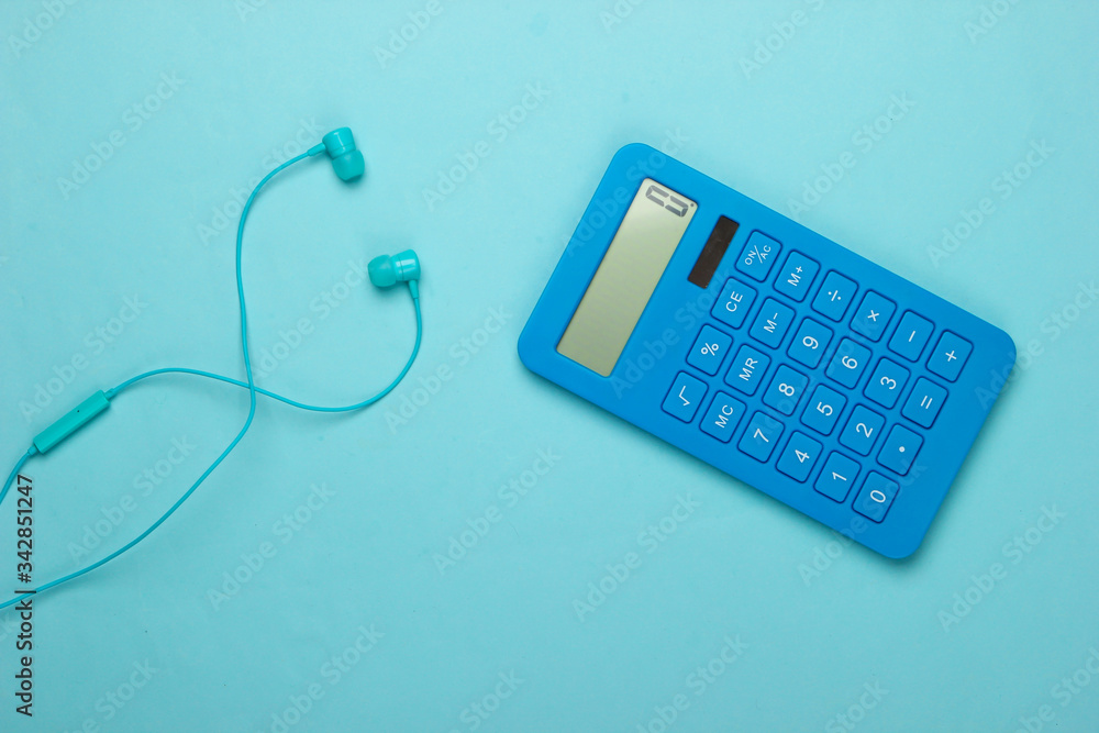 Earphones with calculator on blue background. Top view Earphones with calculator on blue background. Top view