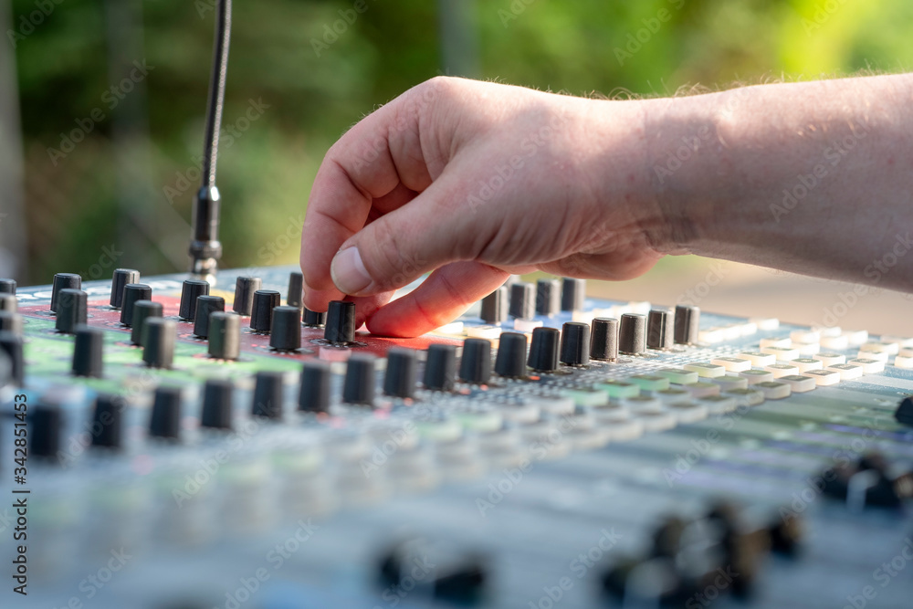 Closeup of a sound engineer at mixing desk at open air - might be a wedding or a concert Closeup of a sound engineer at mixing desk at open air - might be a wedding or a concert