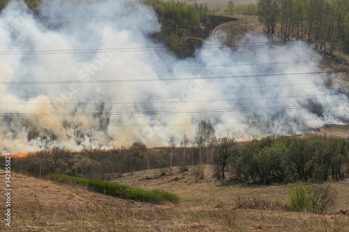 Strong natural fire in Siberia in Russia. Important environmental issues. Landscape with road, fields, hills and poles with electricity.