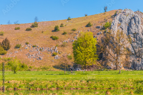 The river Brenz in the Eselsburg valley (Eselsburger Tal) near Herbrechtingen, Heidenheim, Germany on a sunny day. Cyclist riding a bicycle on the road. Travel, tourism, sport concept photo