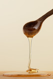 Tasty honey in spoon on yellow background. Thick honey dipping from the wooden honey spoon.