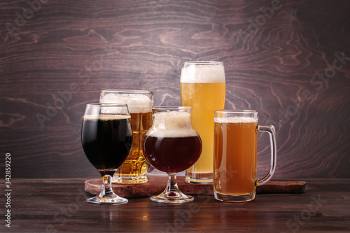 Mugs with different sorts of beer on a wooden table. Beer tasting concept