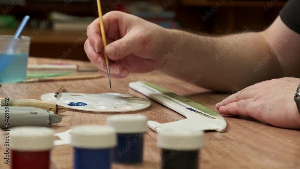 master applies paint onto wooden part of passenger jetliner model with brush at table in room close view slow motion master applies paint onto wooden part of passenger jetliner model with brush at table in room close view slow motion