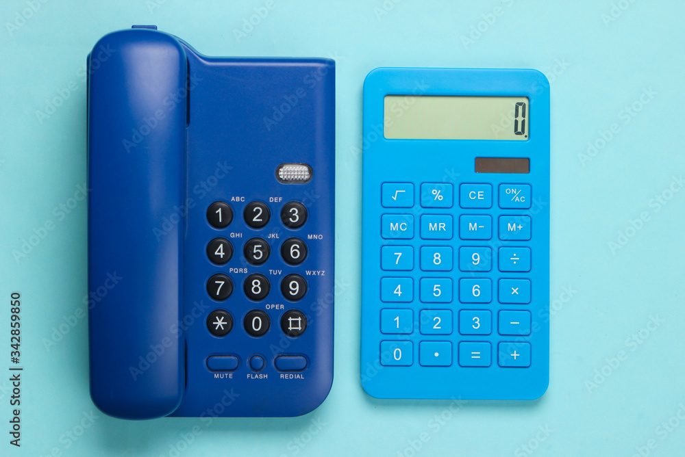 Calculator with a stationary office phone on a blue background. Top view Calculator with a stationary office phone on a blue background. Top view