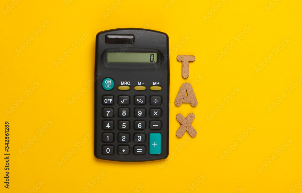 Calculator with the word tax on yellow background. Top view Calculator with the word tax on yellow background. Top view