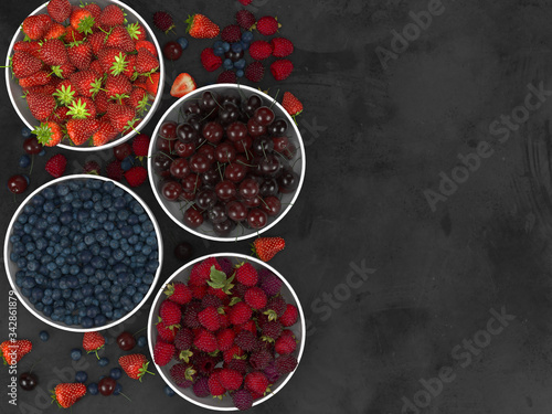 Strawberries, raspberries, 
cherry and blueberries on a black background, background concept and creative layout. Flat lay. Top view.