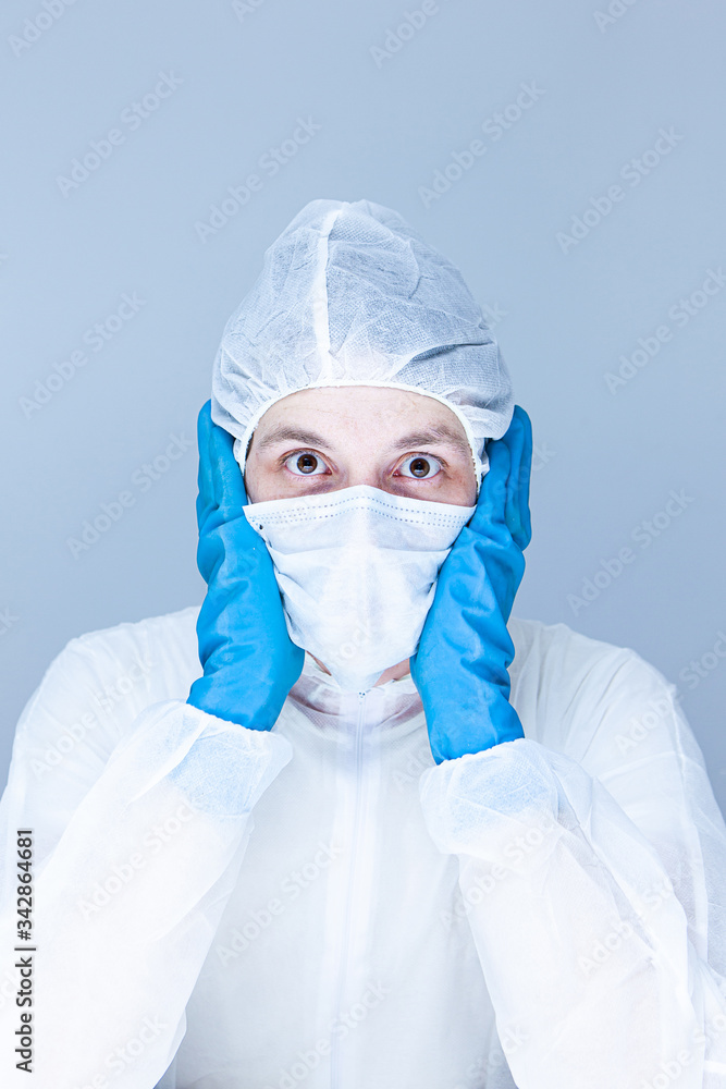 man in protective suit, gloves and mask on his face holding his head pretending to panic or fear. The concept of health. man in protective suit, gloves and mask on his face holding his head pretending to panic or fear. The concept of health.