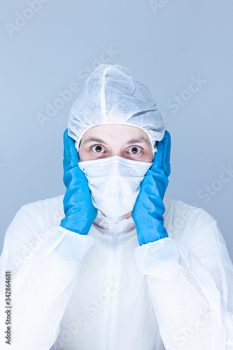 man in protective suit  gloves and mask on his face holding his head pretending to panic or fear. The concept of health.