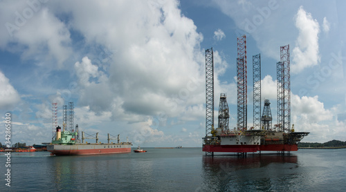 general cargo vessel underway to leave port with jack up rig anchor inside port