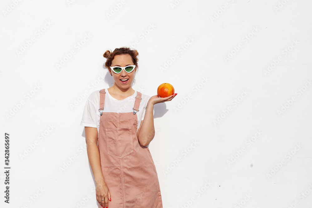 Studio portrait of happy girl, smiling cheerfully, holding ripe grapefruit in hands, standing isolated over white background. Tasty tropical fruit, healthy food, raw food diet Studio portrait of happy girl, smiling cheerfully, holding ripe grapefruit in hands, standing isolated over white background. Tasty tropical fruit, healthy food, raw food diet