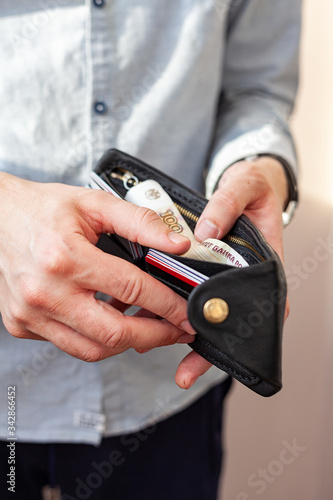 male hands hold a purse. A wallet with little money in it. The concept of poverty and bankruptcy