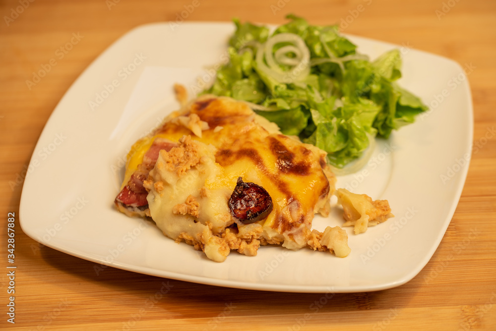 Mashed potatoes baked with meat with lettuce salad on side Mashed potatoes baked with meat with lettuce salad on side