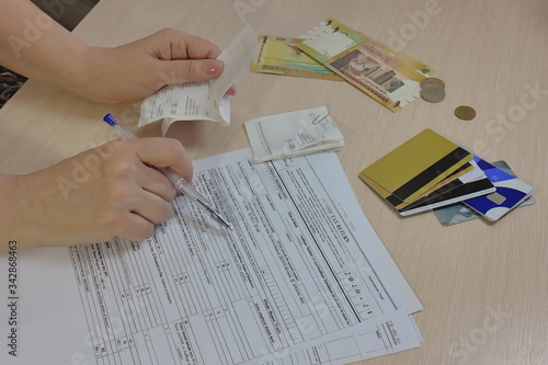 Completing tax form. Hand with pen over tax form on the background of money and credit cards. Selective focus