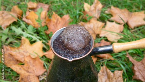 Brewing coffee in a turkish pot - outdoors over the autumn leaves
 photo