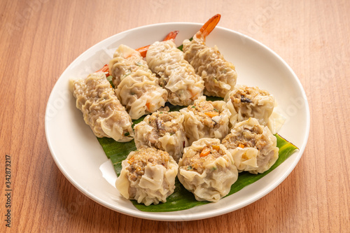 White Dish of Asian Steam  Dumplings  or Dim Sum a Famous Chinese Food  with Pork and Shrimp on  Wood Table.