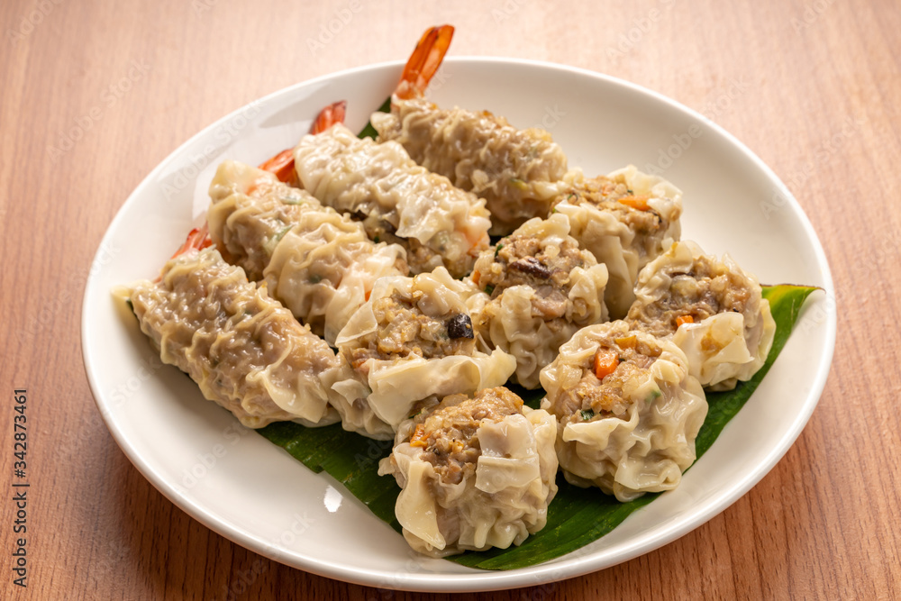 White Dish of Asian Steam  Dumplings  or Dim Sum a Famous Chinese Food  with Pork and Shrimp on  Wood Table.