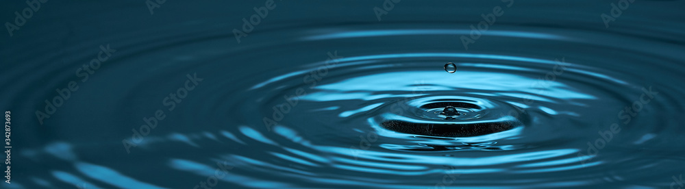 Water drop close up. Blue abstract background water drop and diverging circles. Photo with copy space.