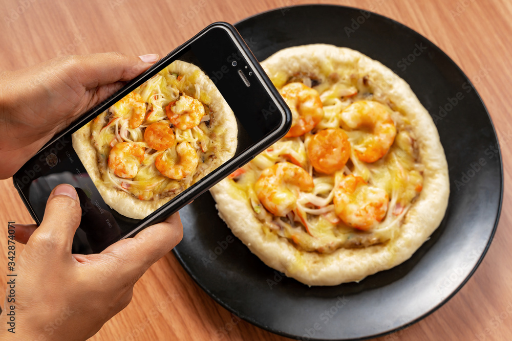 Hand Taking Photo Pizza Cheese with Shrimp, Pork, Imitation Crab Stick and Salted Eggs on White Dish Wood Table. Hand Taking Photo Pizza Cheese with Shrimp, Pork, Imitation Crab Stick and Salted Eggs on White Dish Wood Table.