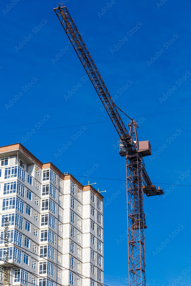 Extensive scaffolding providing platforms for work in progress on a new apartment block,Tall building under construction with scaffolds,Freestanding tower crane on a building site