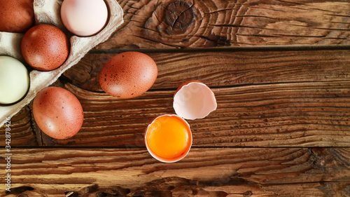 Raw broken colour egg with yellow yolk.Chicken raw, farm eggs on old wooden table .