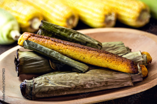 Broa made with corn and wrapped in banana leaf. Typical Brazilian dessert called bread-a-pique bread, Brazilian bread or corn bread. photo