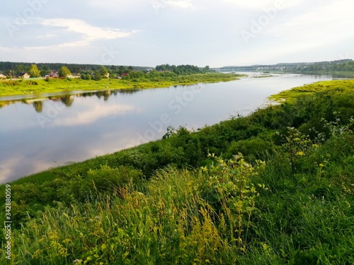 Bend of a beautiful wide calm river Suhona with reflection of clouds and plants on the shore.Vologda region.Russia.