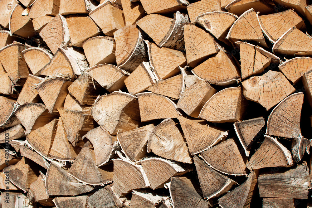 a woodpile made of birch wood, neatly stacked in layers. Close-up photo, cropped
