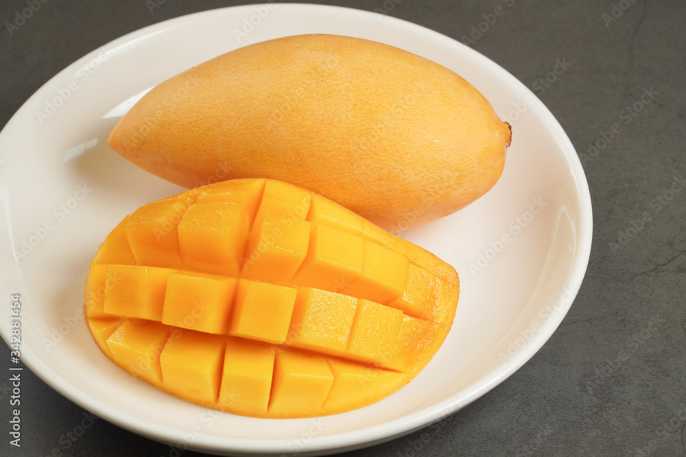 Fototapeta premium Fresh Mango on white plate and black pattern background