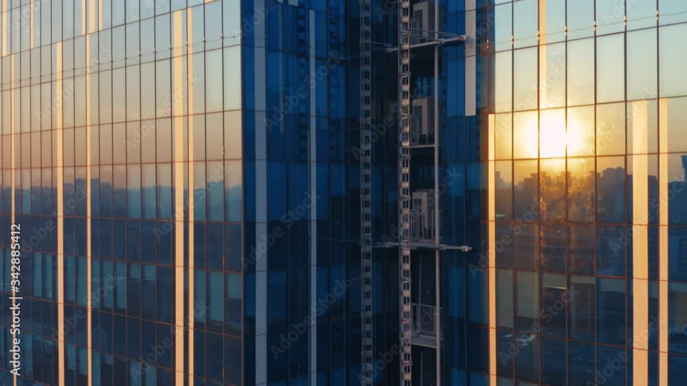 Aerial elevator shot of the modern glass skyscraper exterior with sunshine and reflection on the windows Aerial elevator shot of the modern glass skyscraper exterior with sunshine and reflection on the windows