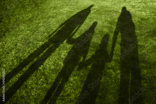 shadows of four family members on fresh green grass lane